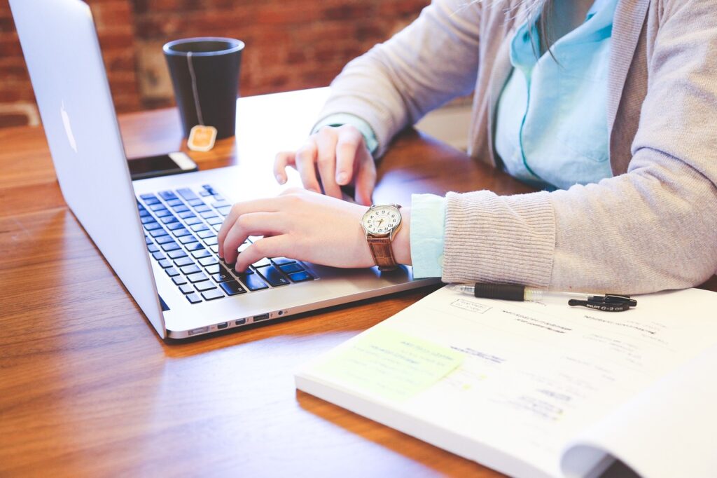 Eine Frau arbeitet an einem Laptop an einem Schreibtisch in ihrem Heimbüro.